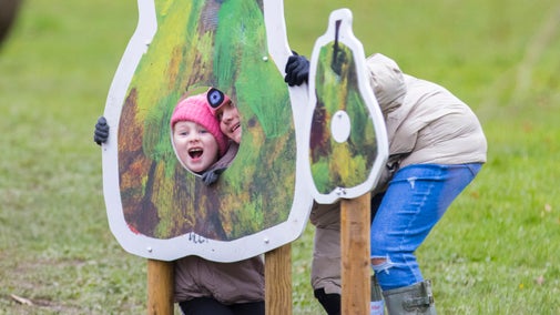 A woman and child pose with their faces through a cut-out in a giant pear illustration on The Very Hungry Caterpillar Trail.